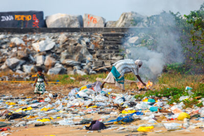 A child girl plays in piles of trash while her mother burns it on the beach of Kollam, Kerala