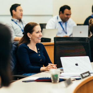 An woman smiling in class with peers.