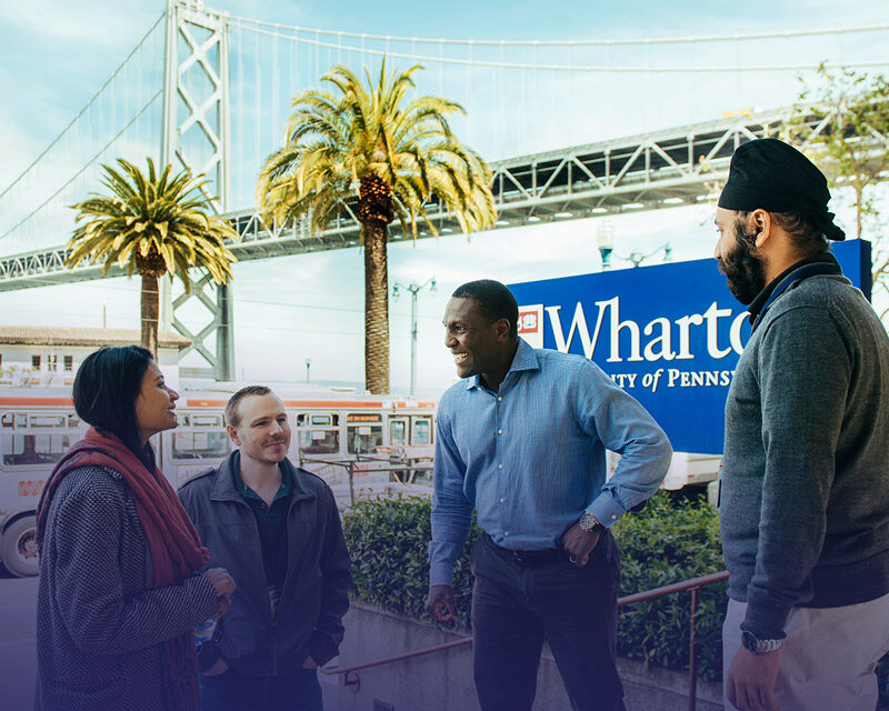 Wharton alumni infront of the Wharton San Francisco campus sign