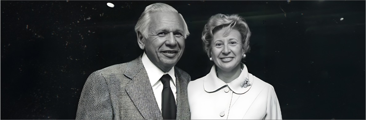 A black and white photo of Leonard and Sophie Davis in formal attire with a dark speckled background.