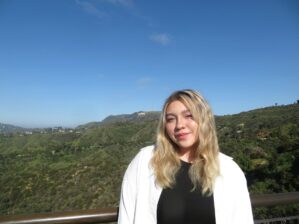 Camila Moreno Juarez, W’27 smiling in front of a green hillside with the Hollywood Sign in the background.