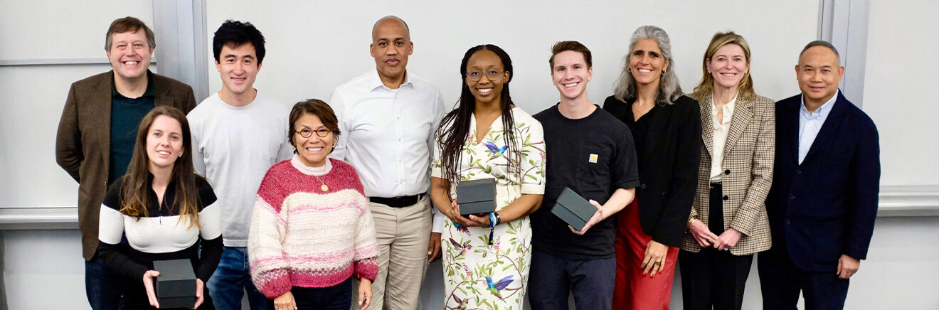 A group of ten people indoors, with four holding black awards