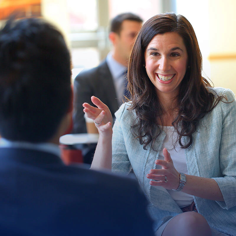 FY25_GOLD_Career_03 A Wharton Career smiles and gestures while talking to alumni