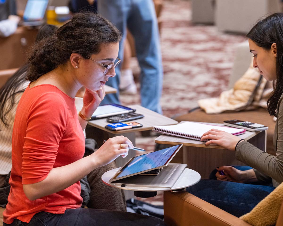 Wharton Online Course Image 3 Two Wharton alumni working with a tablet and notebook at a shared workspace.