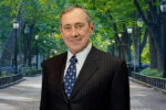 Howard Butcher III Professor Emeritus of Financial Management Marshall Blume wears a pinstripe suit; behind him is a tree-lined pathway with lampposts.