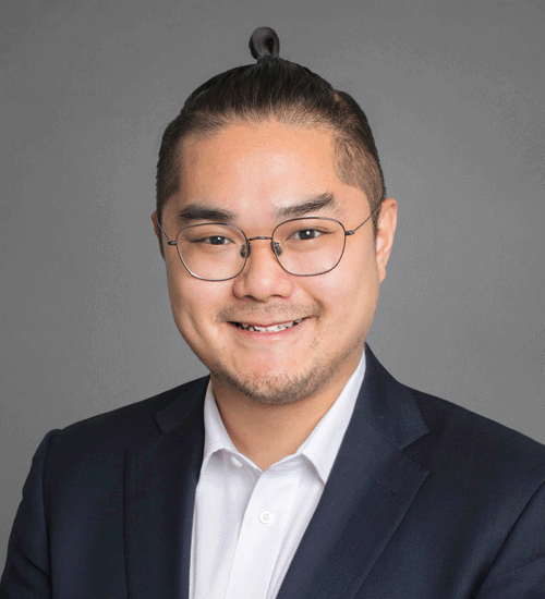 Tim Miao wearing glasses, a suit, and smiling